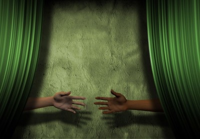 Arms reaching from behind green curtain