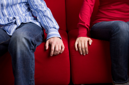 couple on couch with hands close but not touching